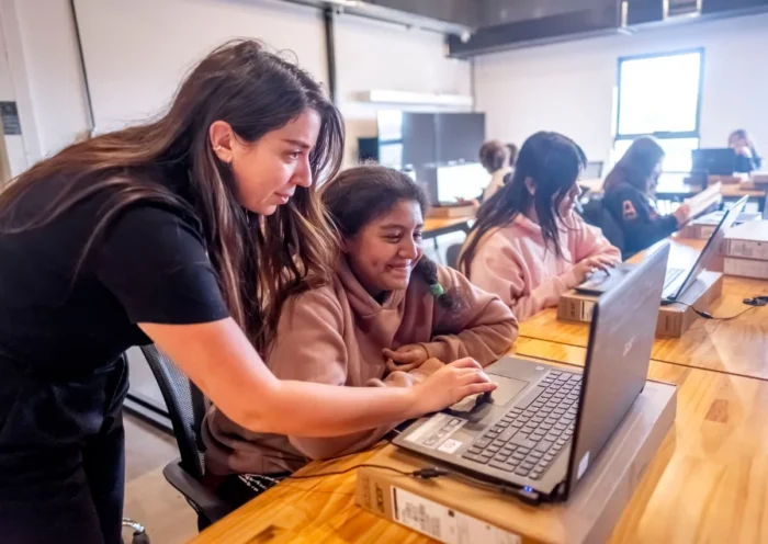 Adolescente siendo guiada frente a la computadora por una profesora. Edicion Game Lab del Club de Chicas Programadoras en ATICMA Mar del Plata