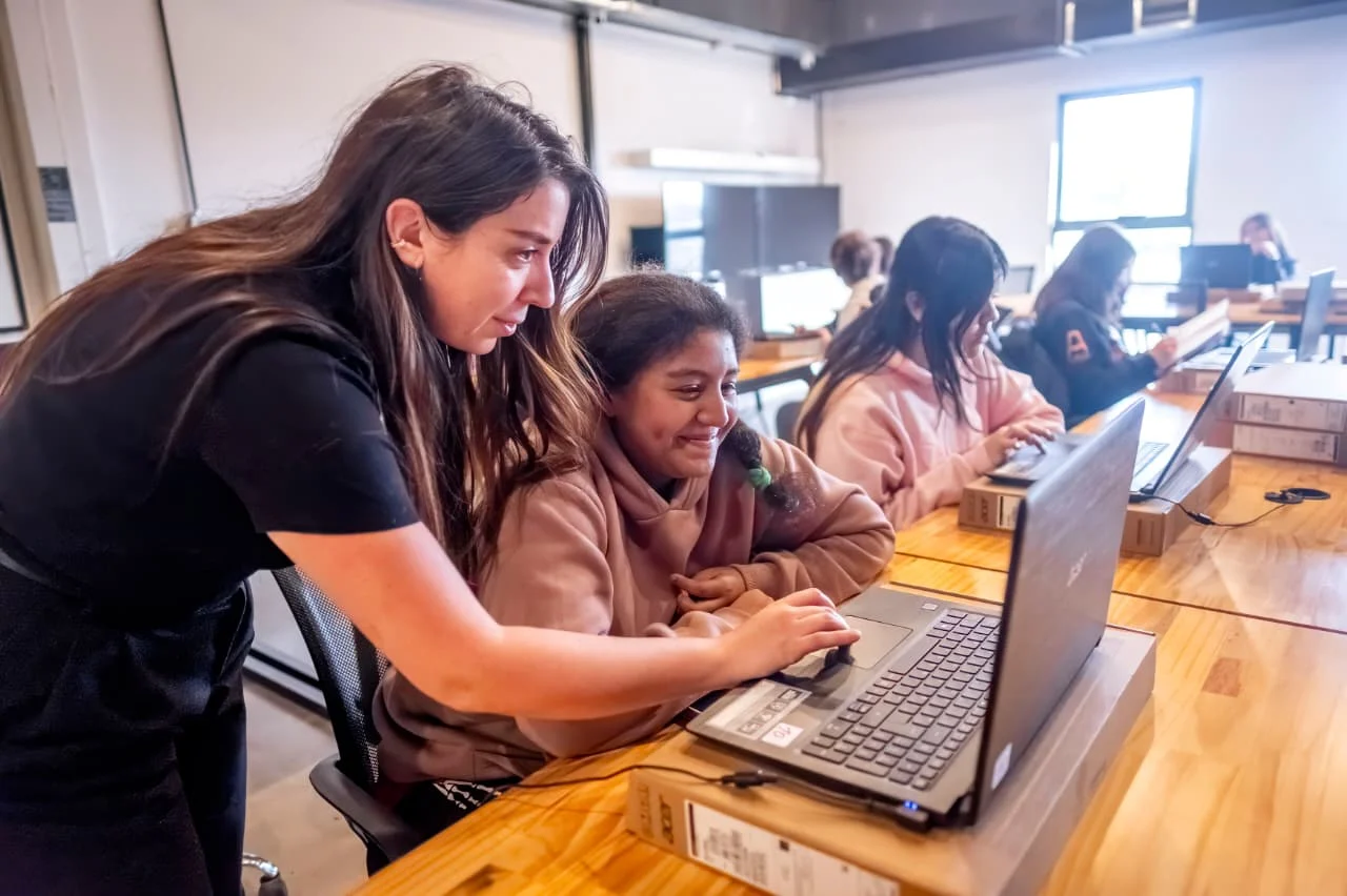 Adolescente siendo guiada frente a la computadora por una profesora. Edicion Game Lab del Club de Chicas Programadoras en ATICMA Mar del Plata